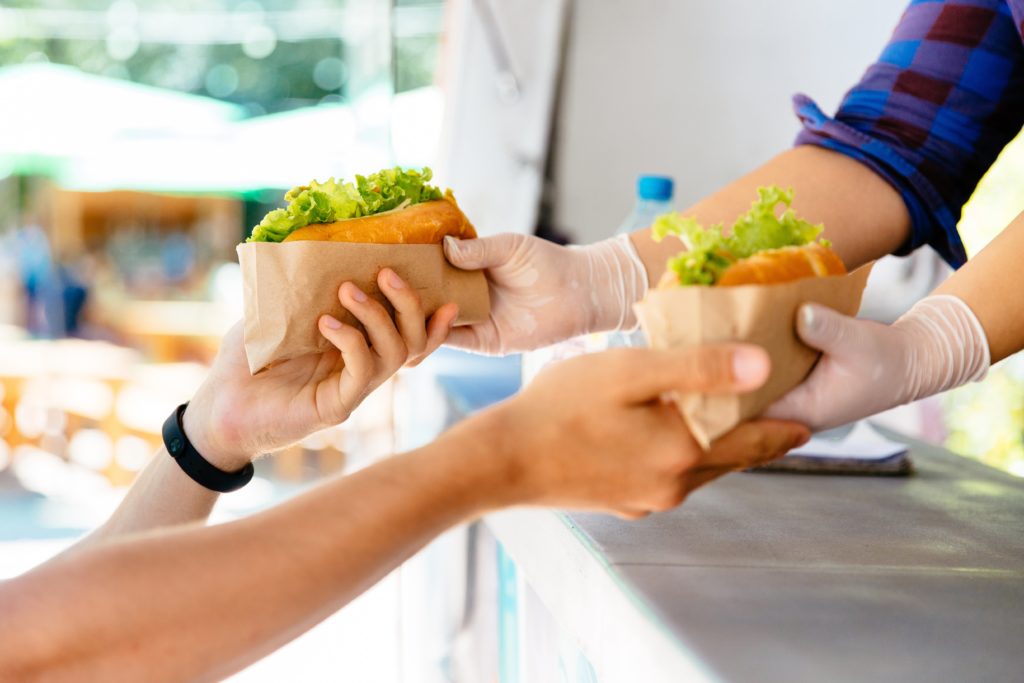 Food vendor handing sandwiches to customers