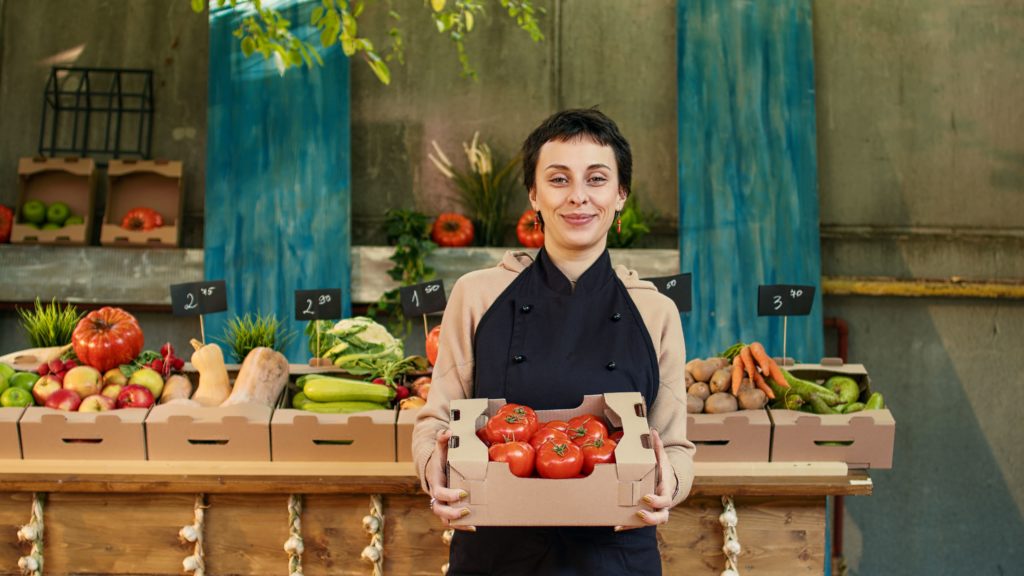 woman at farmers market holding tomatoes