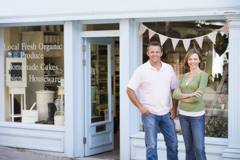 A smiling couple standing in front of their organic food store.