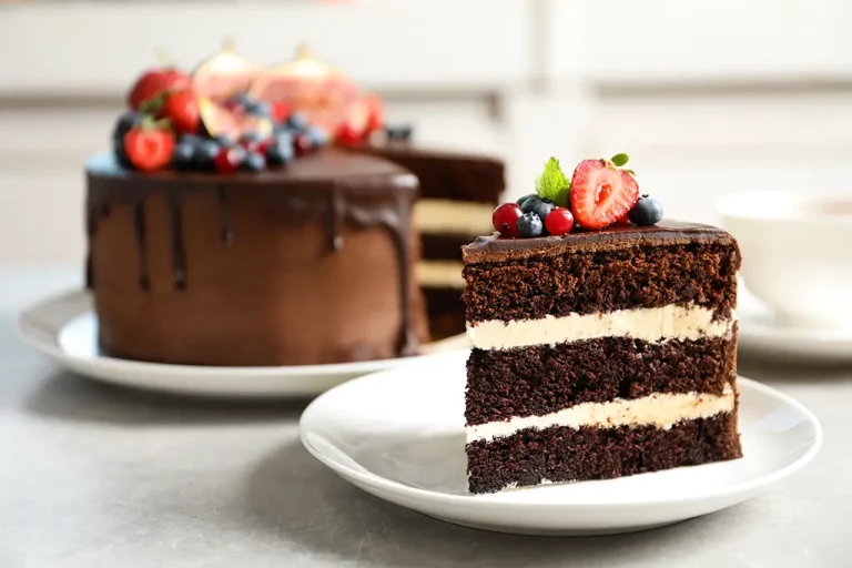 Slice of chocolate cake with butter cream frosting layers topped with berries.