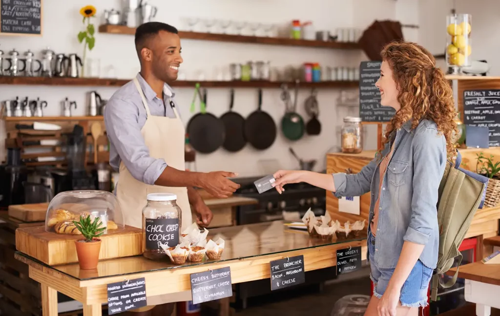 Person handing their credit card to cafe staff.